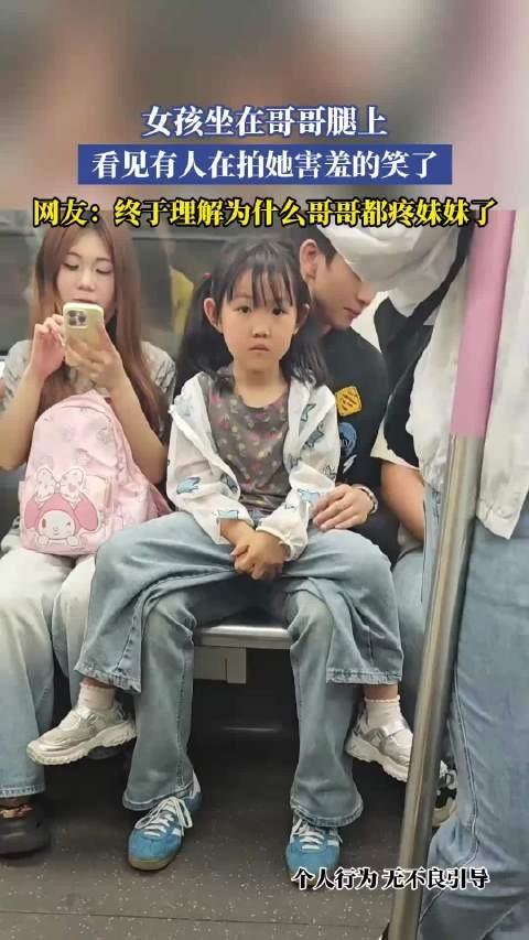 女孩坐在哥哥腿上，看见有人在拍她害羞的笑了