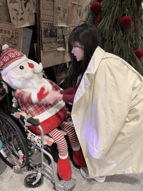 李一桐俯身轻触玩偶，姿态温柔舒展。