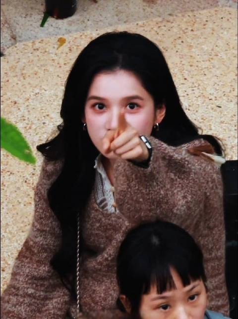 张婧仪身着棕色毛衣，搭配白色内搭，长发垂肩，在户外场景中或凝视或回眸…