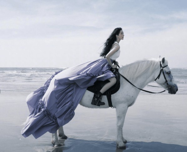 杨幂骑乘白马立于海边，紫纱裙摆随风轻扬。