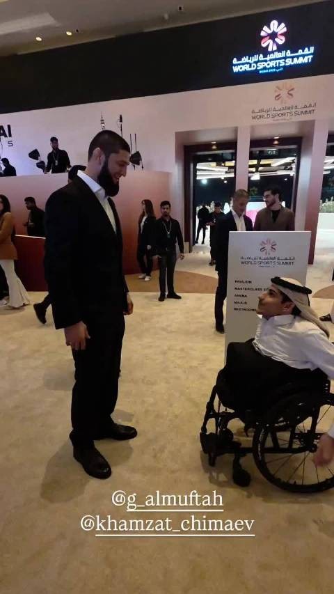 “车臣狼王”坎扎特·奇马耶夫（Khamzat Chimaev）与一个坐在轮椅的人合照