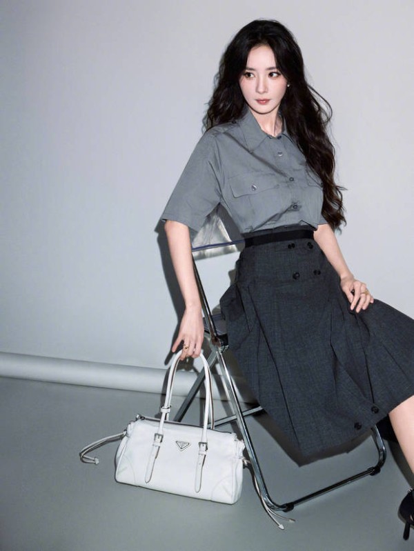 杨幂倚椅而坐，手搭白包神态从容。