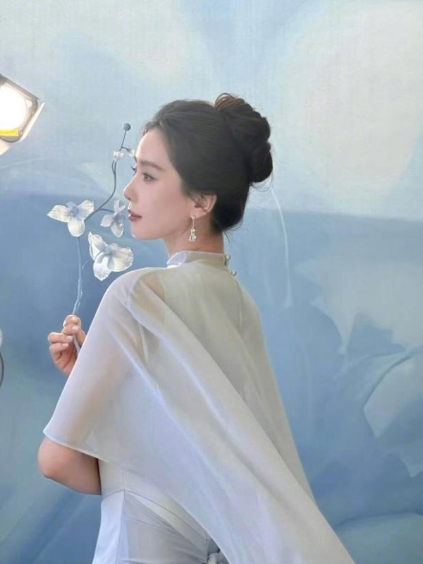 刘诗诗侧立持花,冰蓝轻纱随风轻扬。