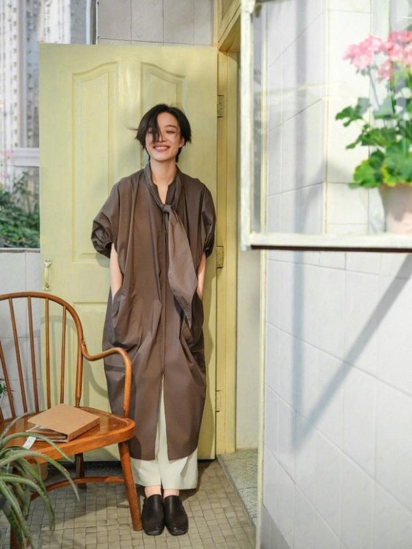 倪妮立门前，咖色裙笑眼明媚。