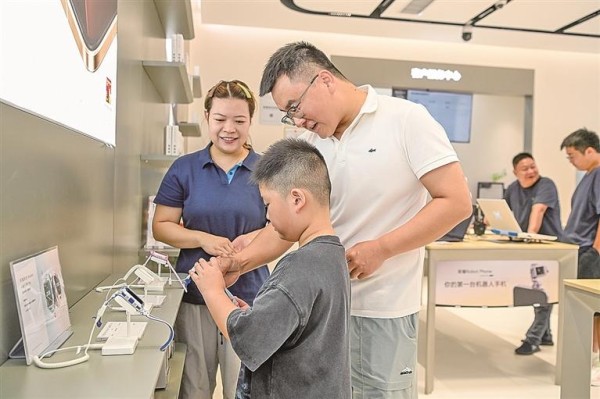 江西宜春市袁州区,家长带着孩子挑选电话手表。周亮摄/光明图片
